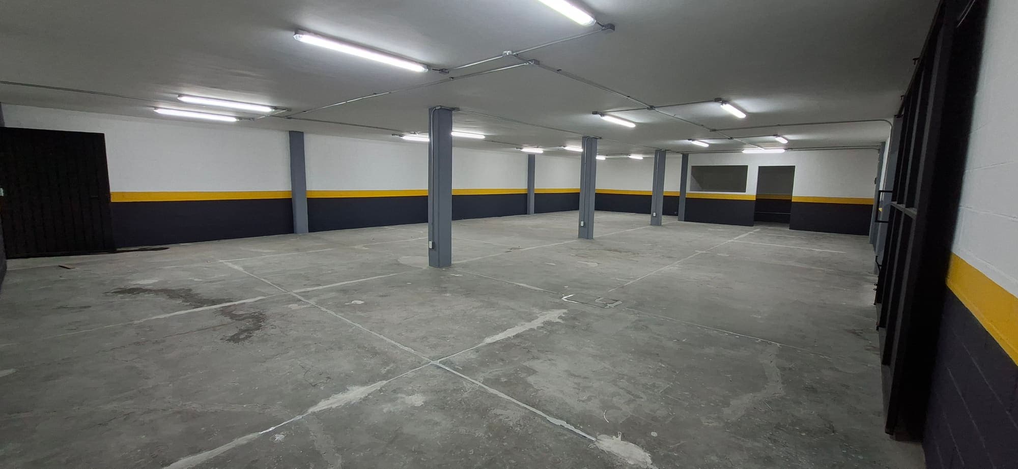 La misma área de techo bajo vista hacia el fondo, con piso de concreto despejado entre las columnas.