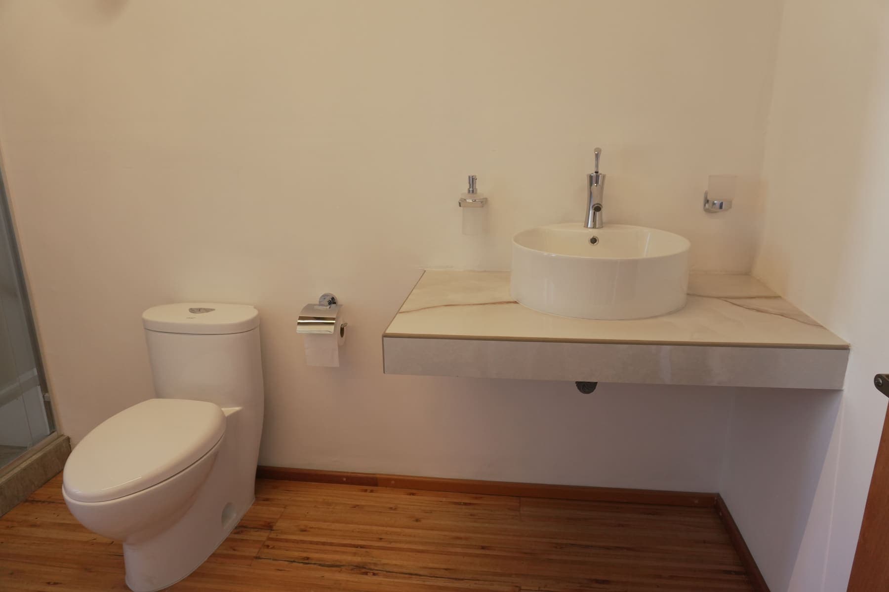 Baño del camerino: lavabo de sobreponer sobre cubierta de mármol y sanitario.