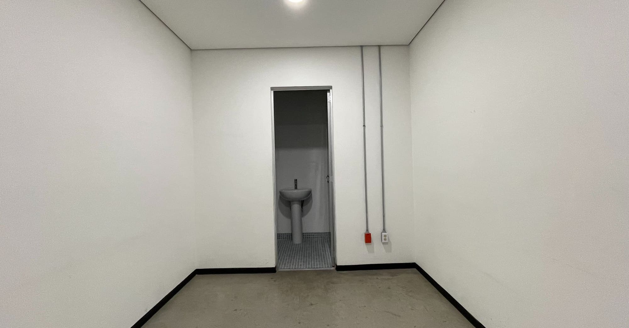 Camerino de muros blancos con baño propio al fondo.