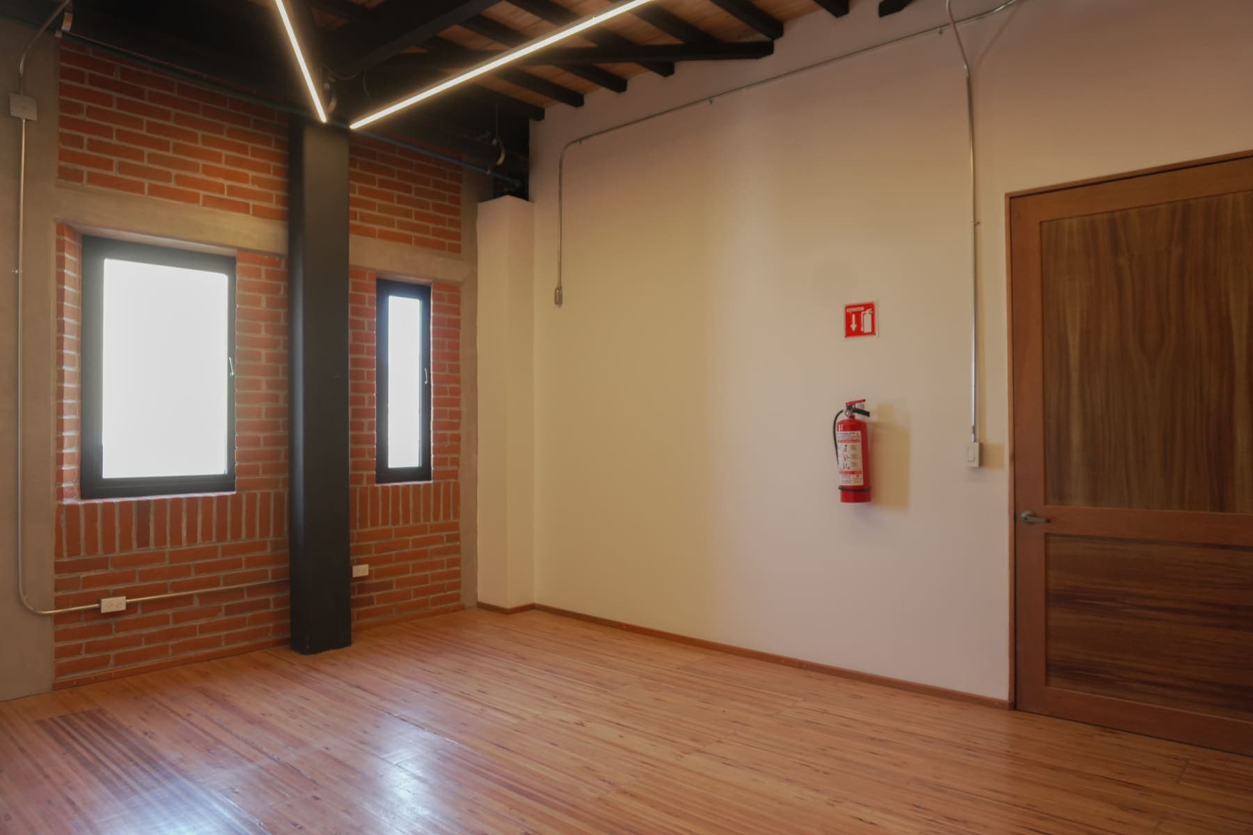 Esquina de un camerino, con dos ventanas cuadradas y columna metálica negra.