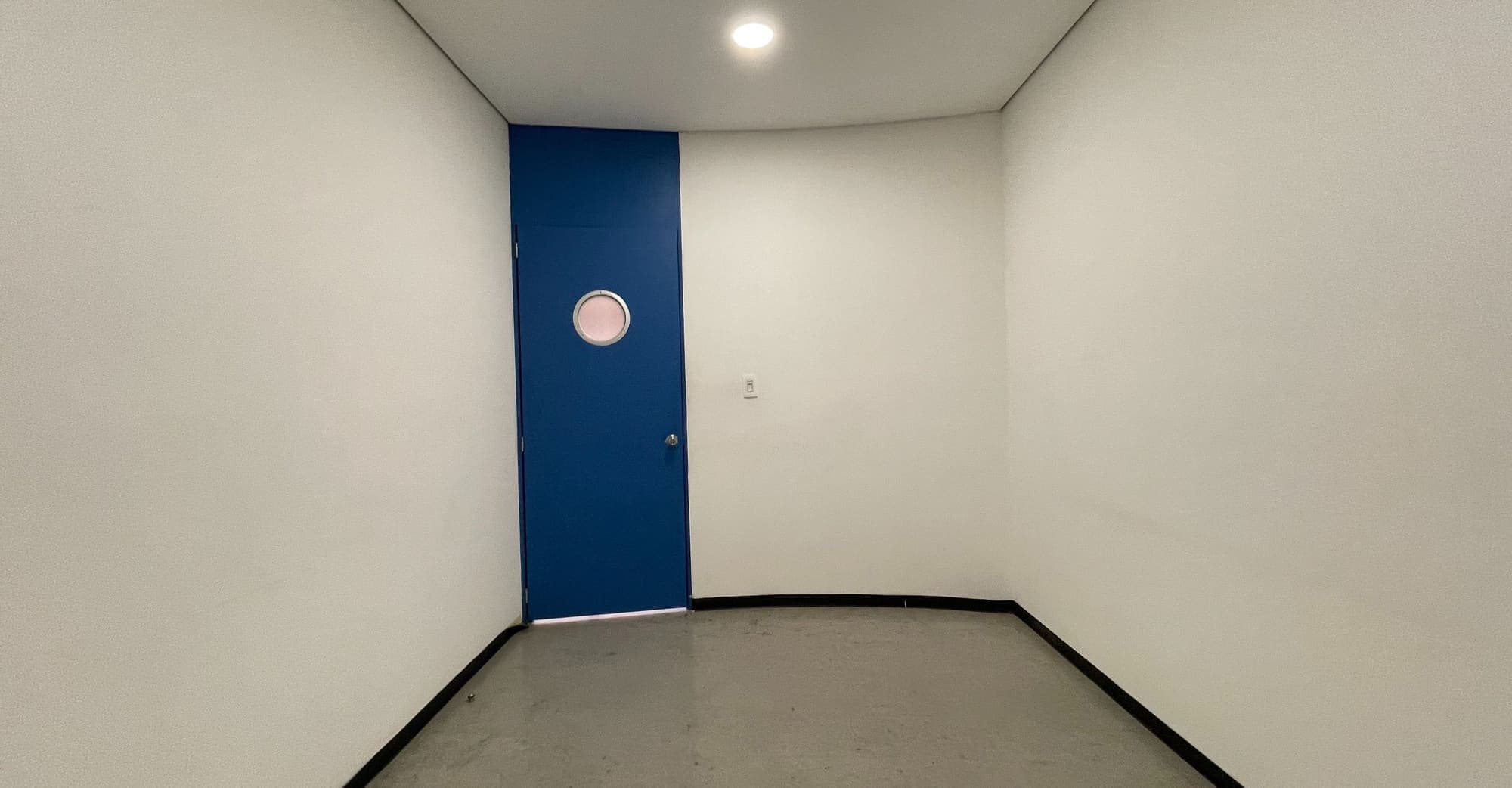 Camerino vacío con puerta azul de ojo de buey.