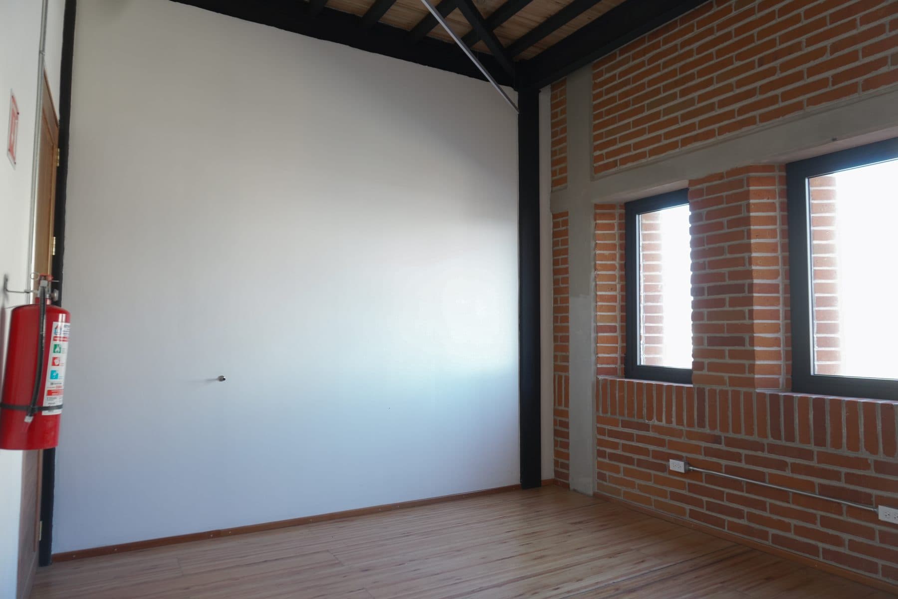 Camerino con muro blanco corrido y una ventana abierta al muro de ladrillo.