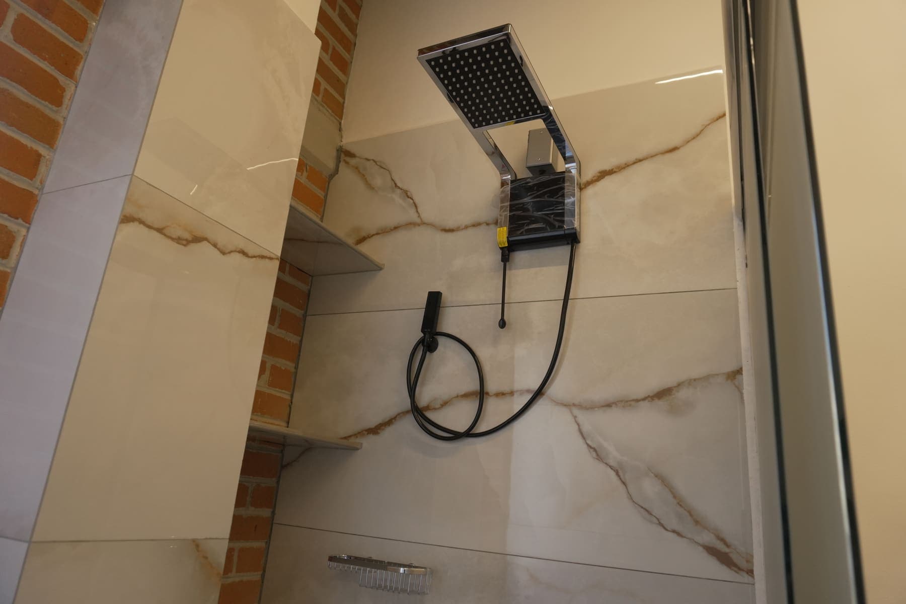 Regadera del camerino, con muro de mármol y regadera de techo.