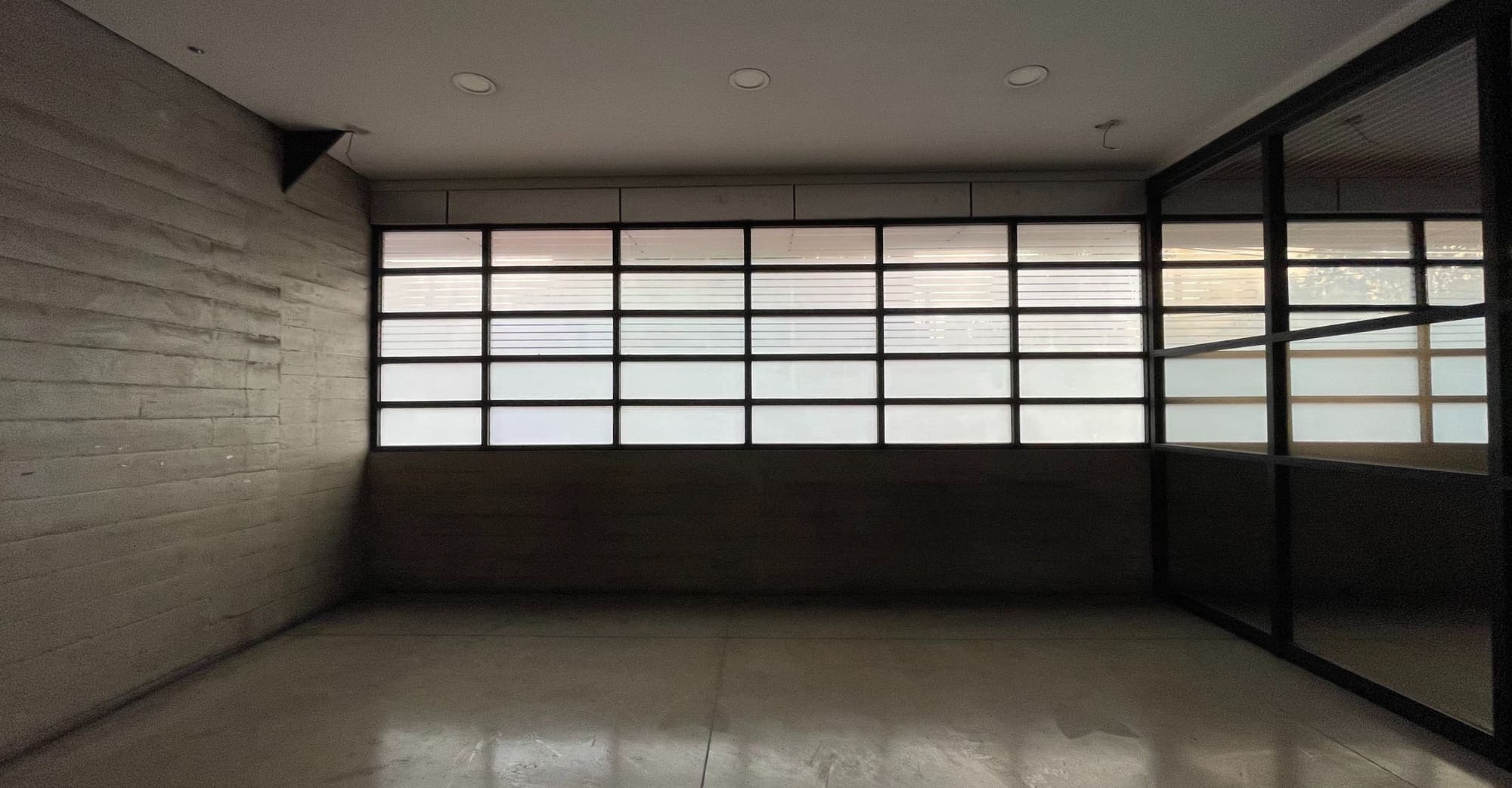 Sala de planta baja con muro de concreto y ventanal esmerilado.