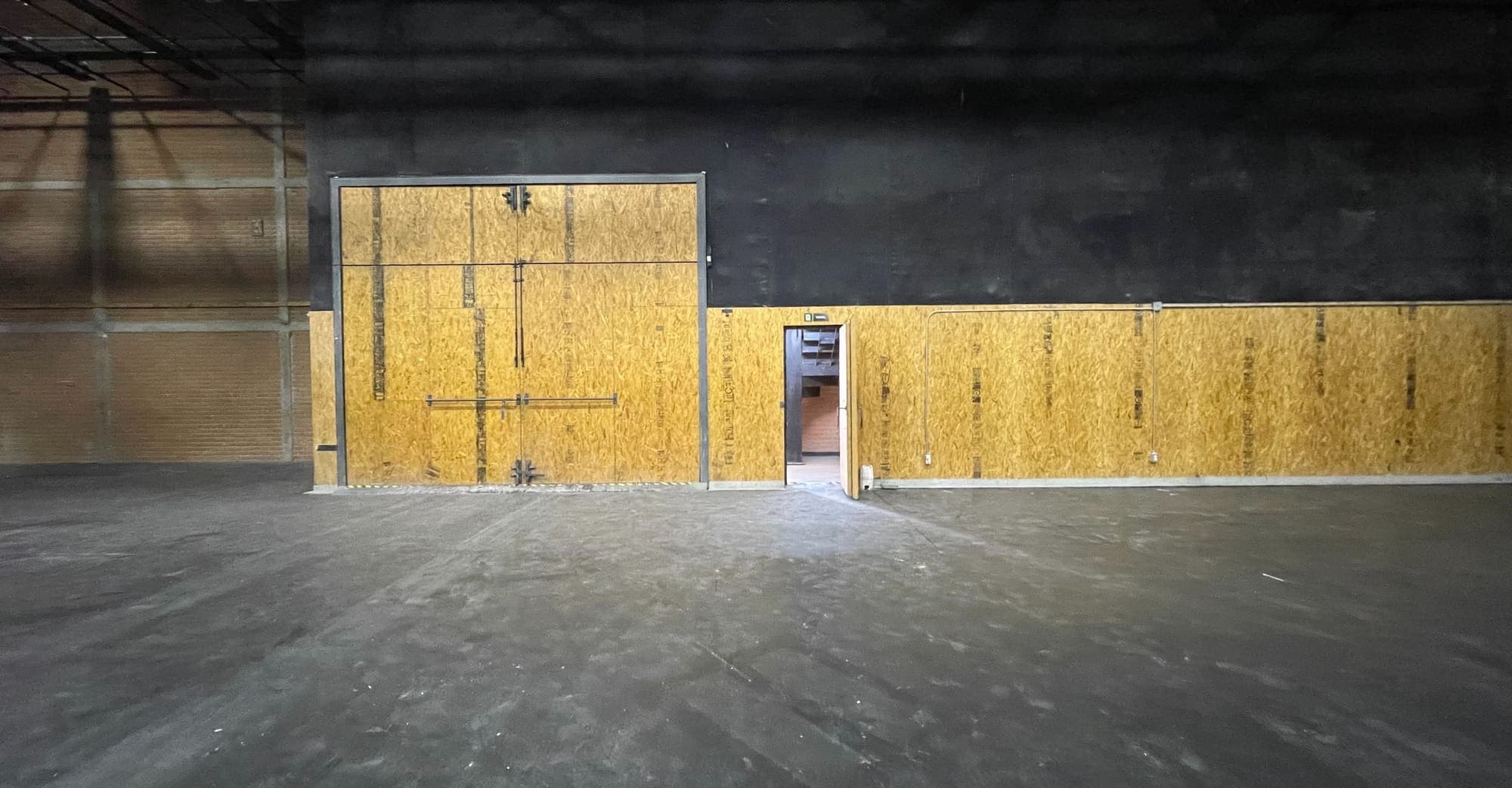 El portón de madera del foro, con una puerta de servicio abierta a su lado.
