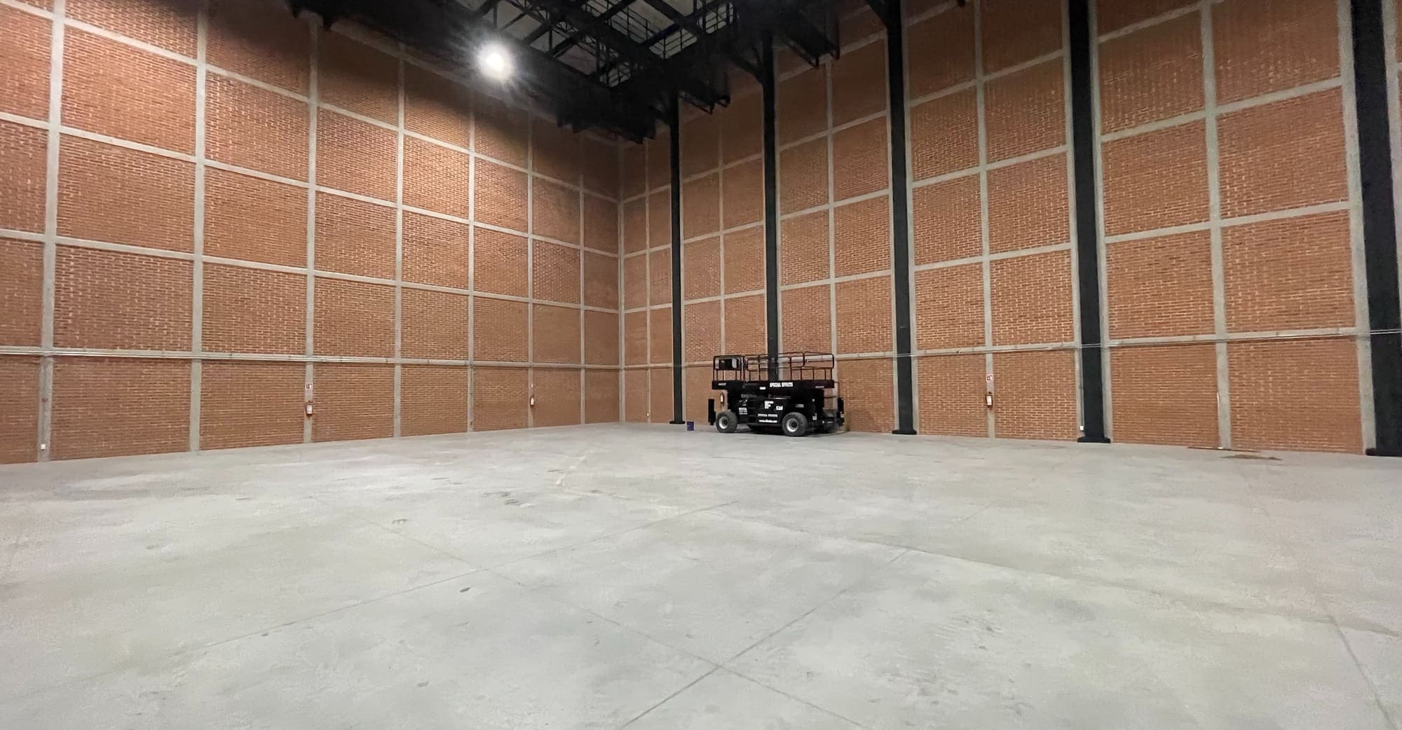 Costado de la nave: retícula de concreto sobre ladrillo hasta la estructura del techo.