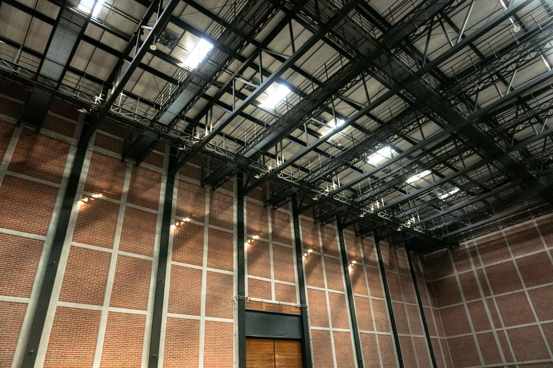La parrilla vista desde abajo: pasarelas metálicas, luminarias y la estructura completa del techo.