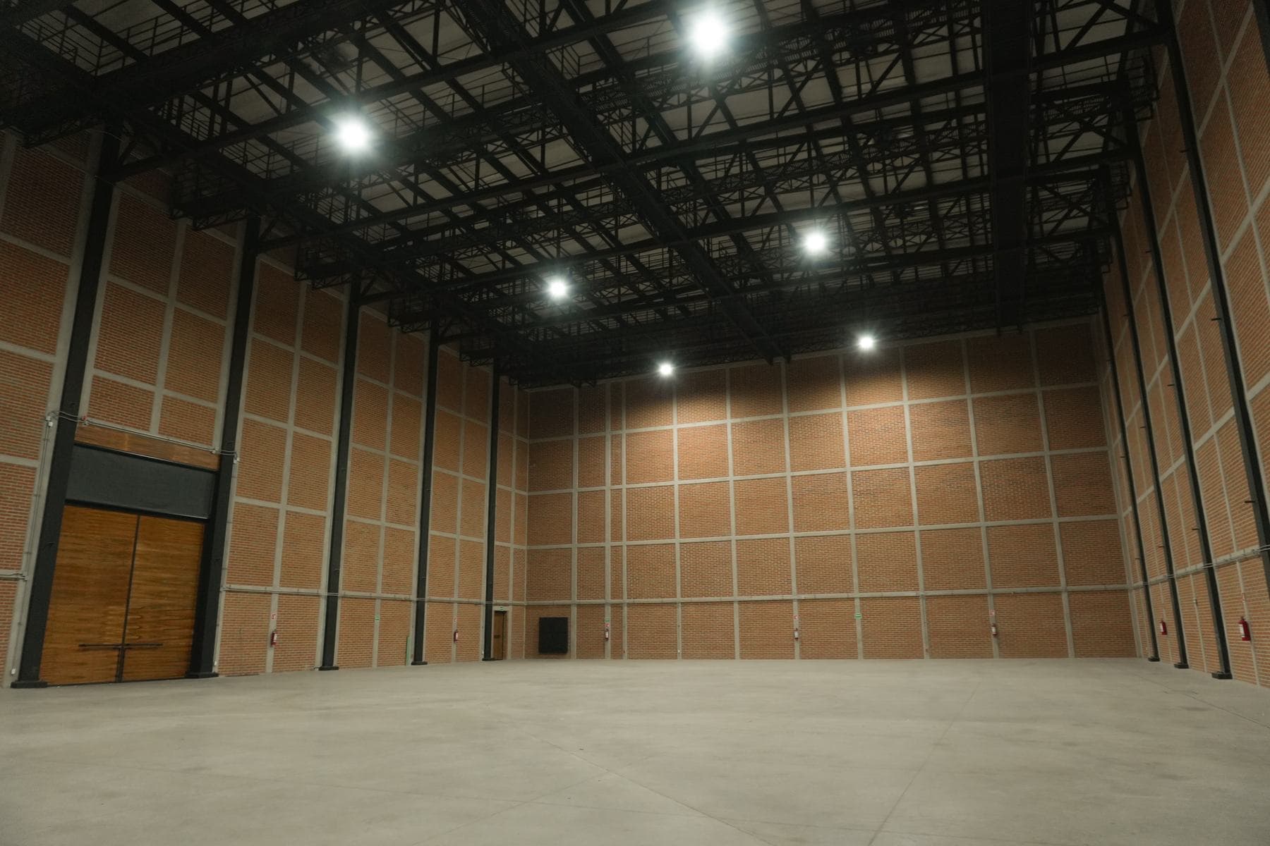 El portón de madera a un costado de la nave, con el piso de concreto libre en toda su extensión.