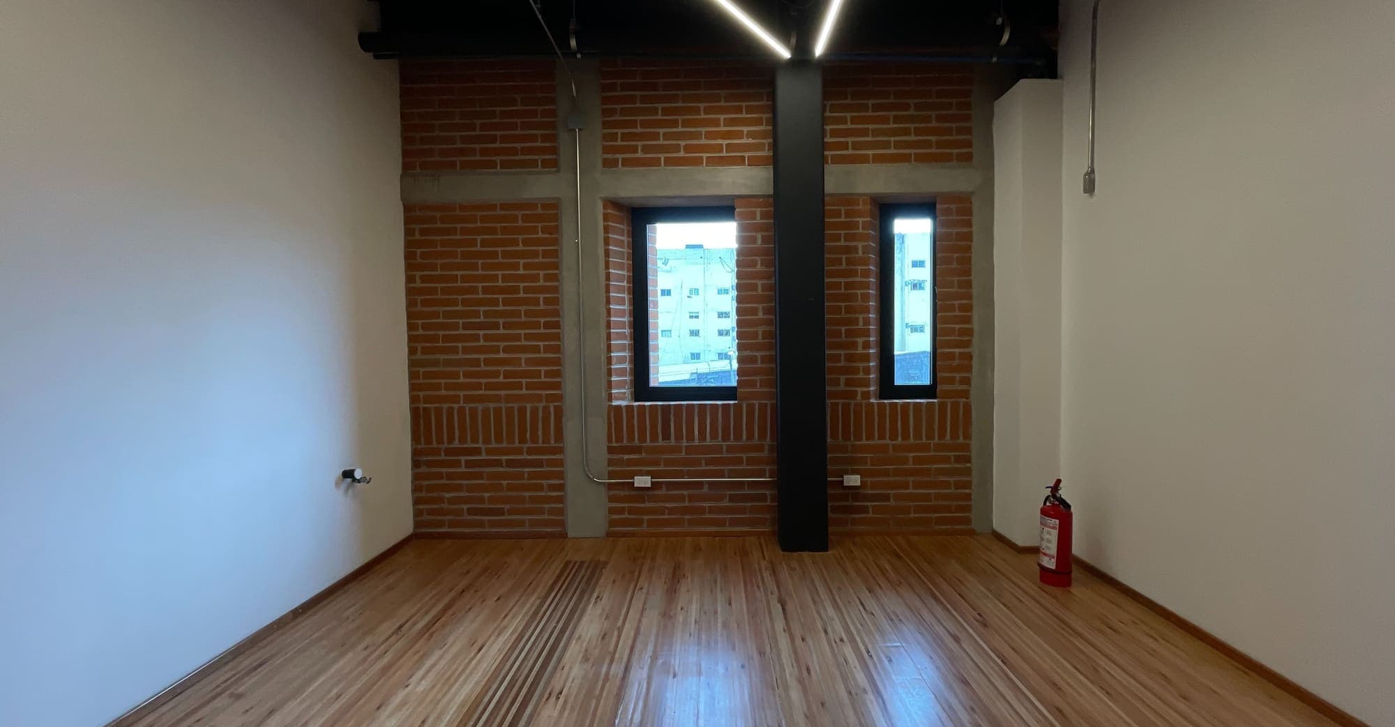 Cuarto de duela con muro de ladrillo y dos ventanas estrechas.