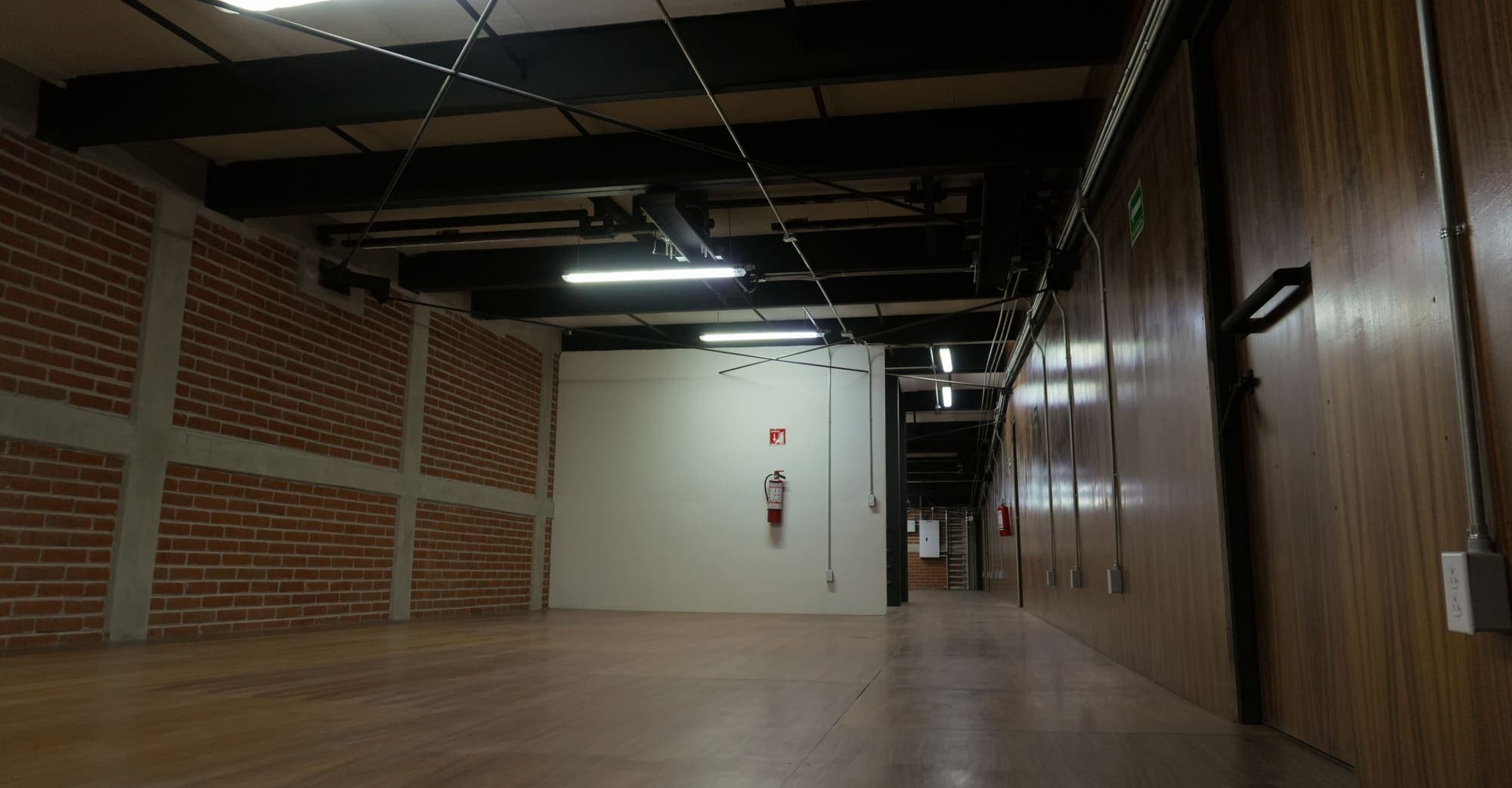 El acceso a la planta, con puerta blanca al fondo y la instalación vista bajo la losa.