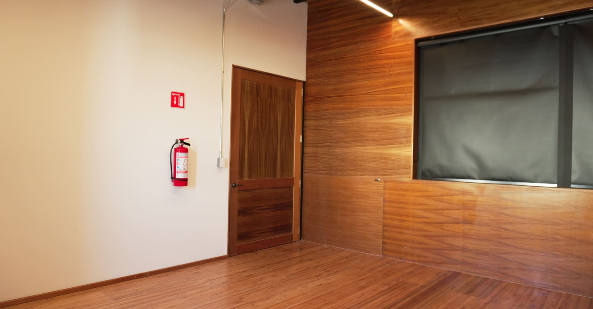 Sala de lambrín de madera con una puerta de madera y un tablero oscuro montado en el muro.