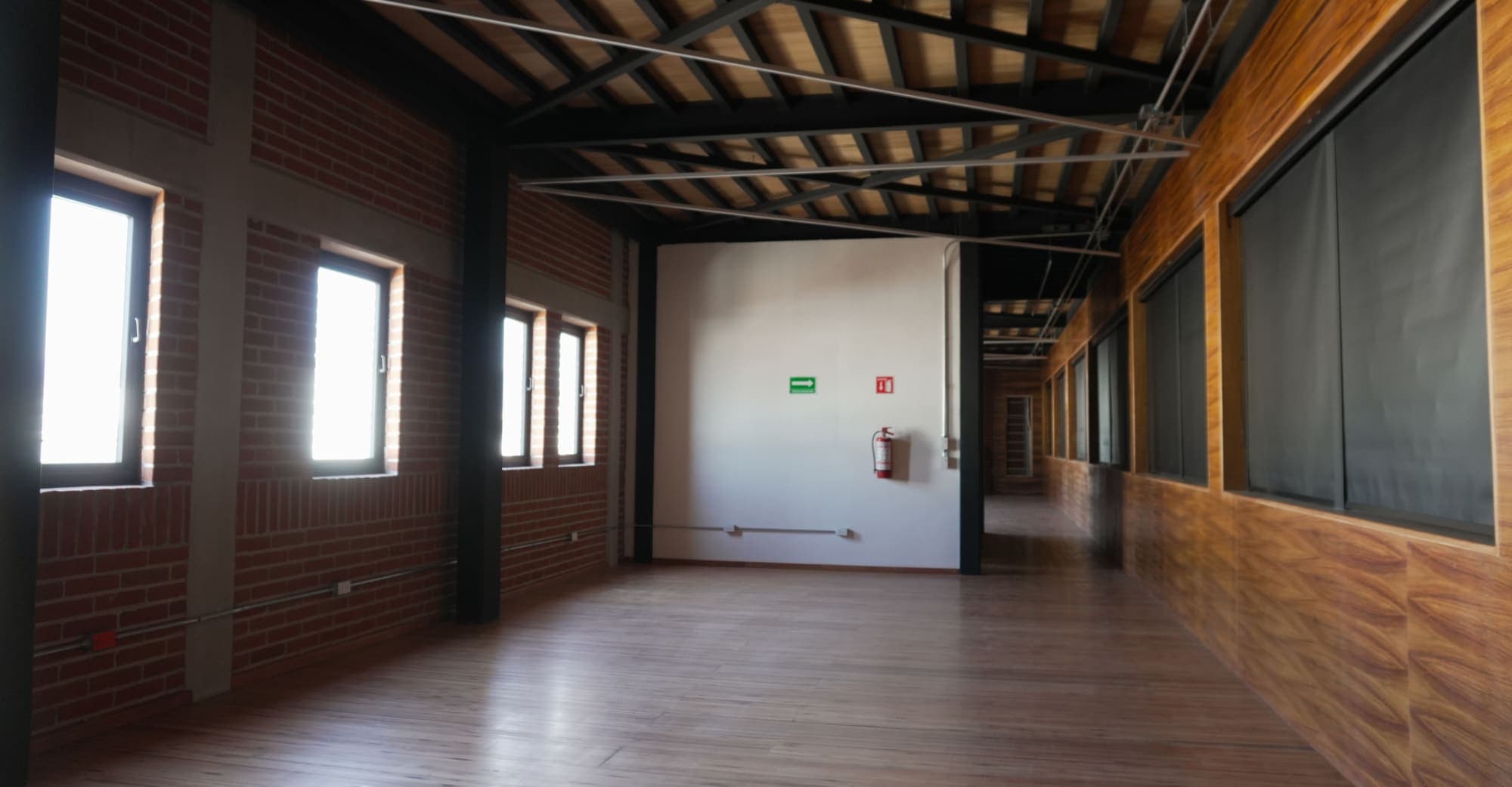 El fondo de la sala de viga vista, con la duela corrida y el lambrín de madera.